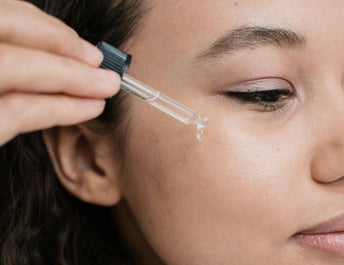 Woman applying jojoba oil to face 