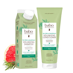 Babo Botanicals tea-free and coconut-free volumizing shampoo and conditioner set in light green packaging props on a white background.