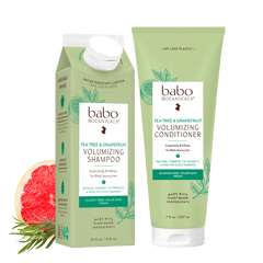 Babo Botanicals tea-free and coconut-free volumizing shampoo and conditioner set in light green packaging props on a white background.