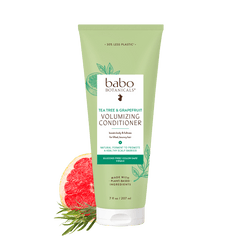 A tube of babo Botanicals Tea Tree & Grapefruit Volumizing Conditioner, shown on a white background with a sliced grapefruit and green leaves graphic at the bottom left.