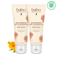 Two tubes of Babo Botanicals moisturizing oat and calendula body lotion on a black background.