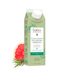 A 16 fl oz carton of babo Botanicals Tea Tree & Grapefruit Volumizing Shampoo, shown on a white background with a sliced grapefruit and rosemary garnish.